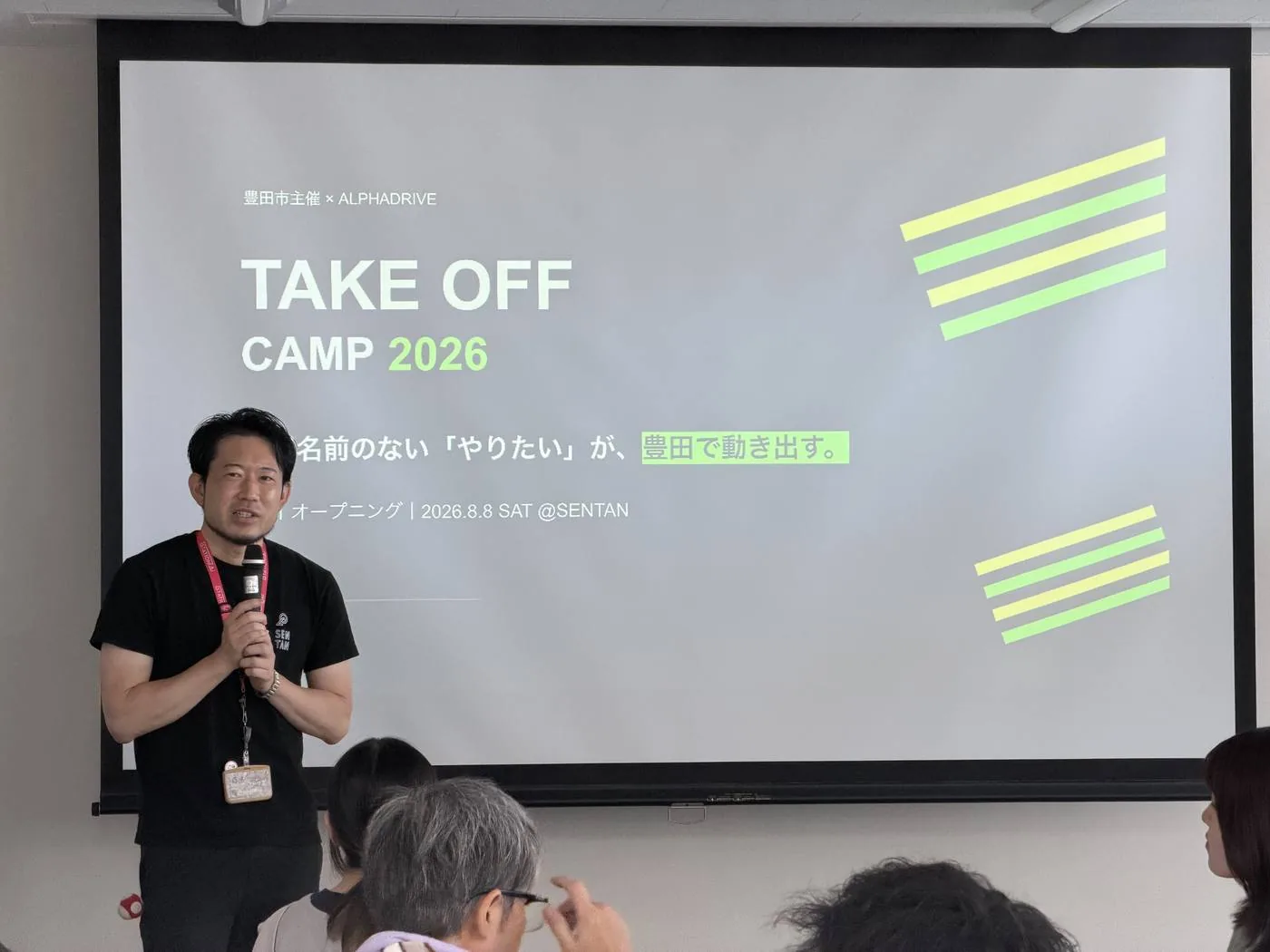 TAKEOFF Campのスクリーンを前に、進行役の石川真之が初日の説明をする様子
