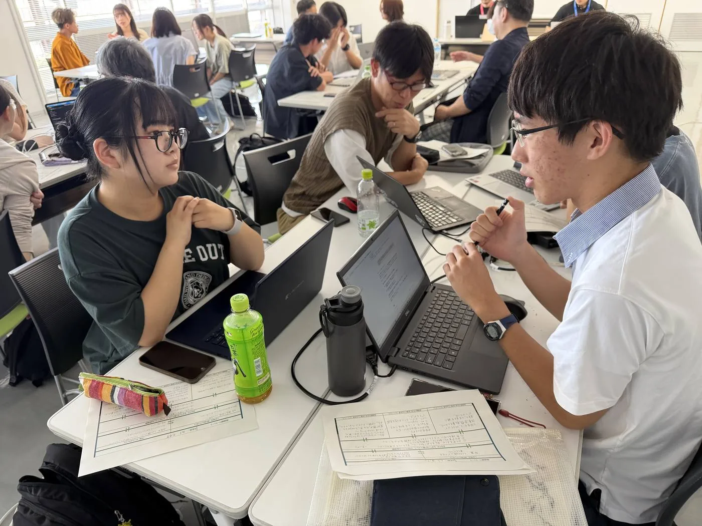 Day1、自分のアイデアについてノートパソコンを前に話し合う参加者
