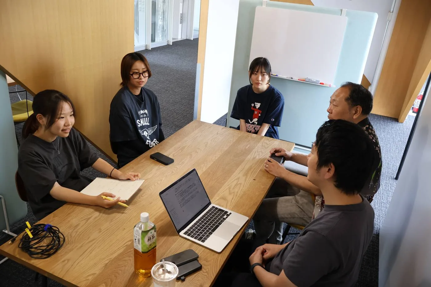 ノートパソコンを囲み、チームでアイデアについて話し合う参加者