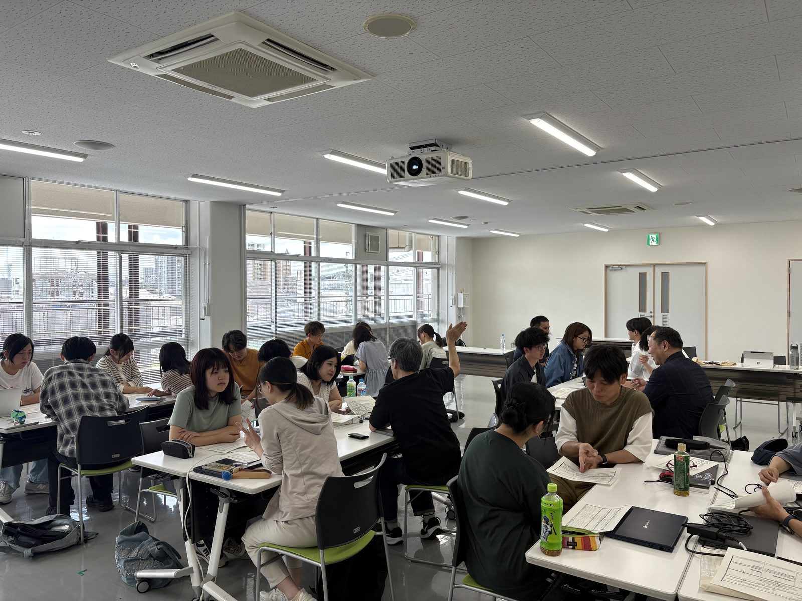 会場のテーブルで、参加者がそれぞれの手元の資料やパソコンに向かって作業する様子