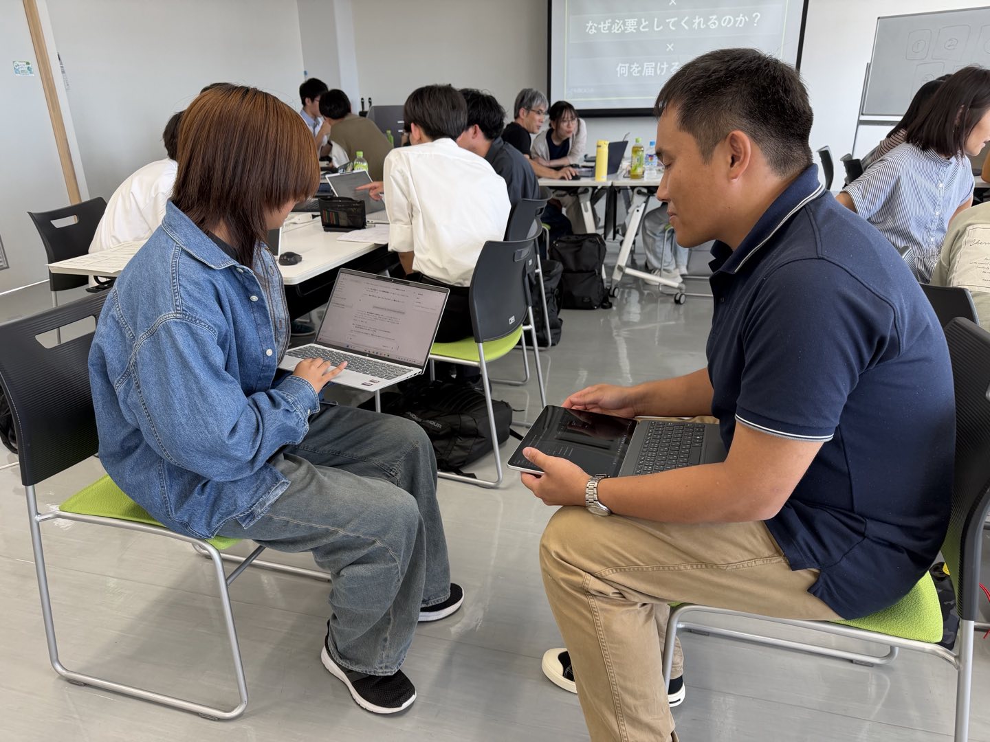 ノートパソコンを手にした参加者どうしが、椅子を向かい合わせて話している様子