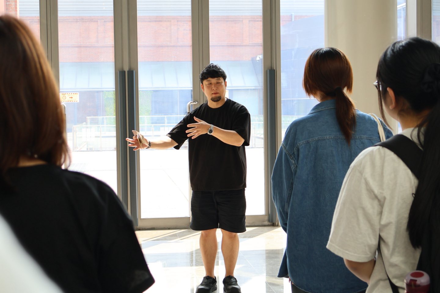 記念館のエントランスで、参加者に囲まれながら身振りを交えて話す土井雄介さん