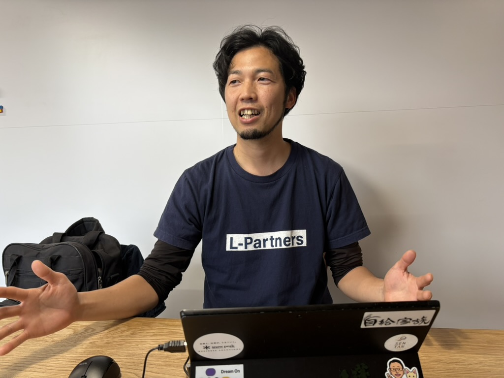 L-PartnersのTシャツを着て、事業について話す辻竜也さん